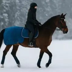 Jazda konno podczas okresu jest możliwa. Kobieta w zimowym stroju na brązowym koniu w śnieżny dzień.