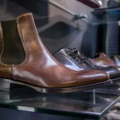 Brązowe sztyblety i inne eleganckie buty męskie na półce. Dowiedz się, jak dobrać sztyblety, by wyglądać stylowo.