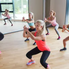 Kobiety ćwiczą przysiady podczas zajęć, przygotowując się do kursu instruktora sportu.