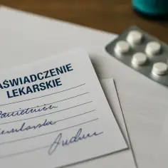 Zaświadczenie lekarskie z receptą i tabletkami na drewnianym tle.