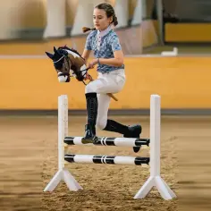 Dziewczynka na kiju, udająca konia, skacze przez przeszkodę. To właśnie jest hobby horse – zabawa w jeździectwo.